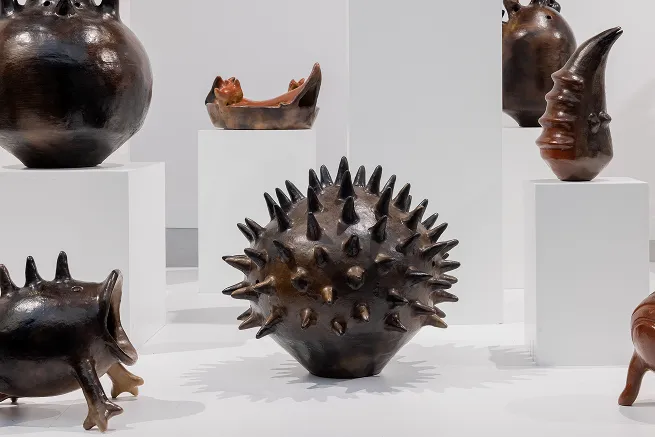 Vases céramiques sombres sur socles blancs, dont une pièce couverte de pointes.