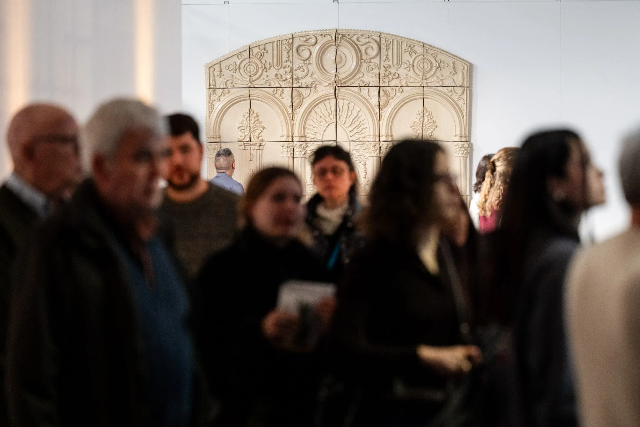 Visitors in front of a large white ceramic altarpiece.